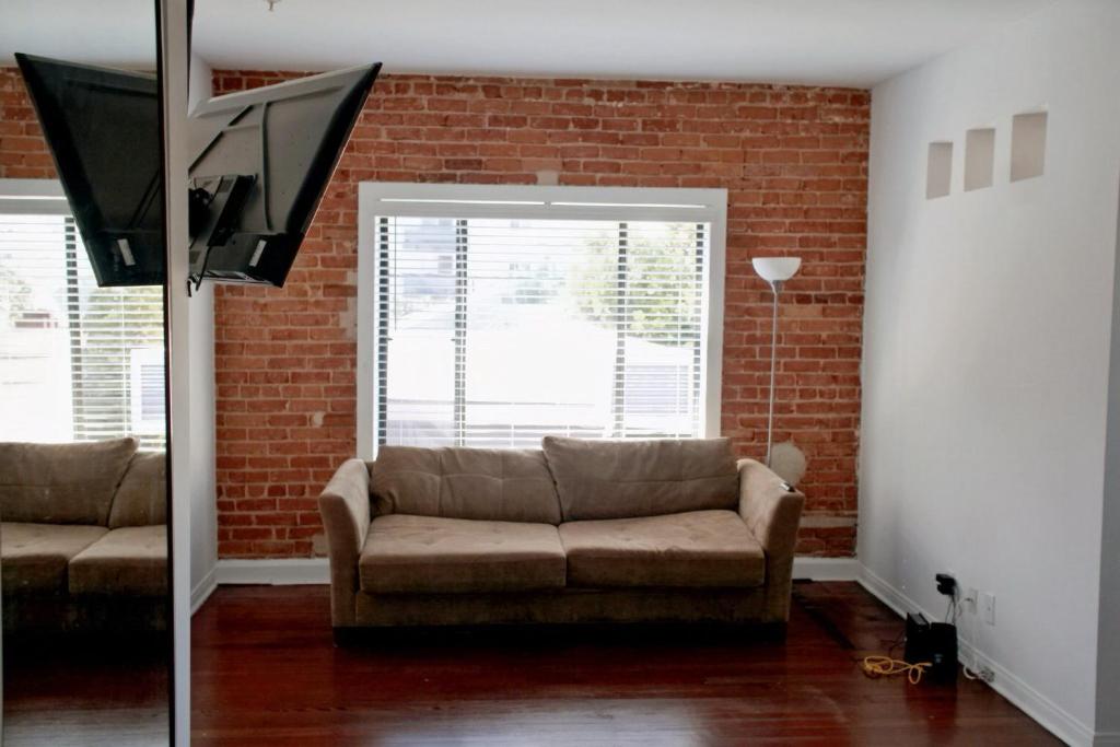 a living room with a couch and a brick wall at Melrose Gem: Stylish Living near Iconic Landmarks in Los Angeles