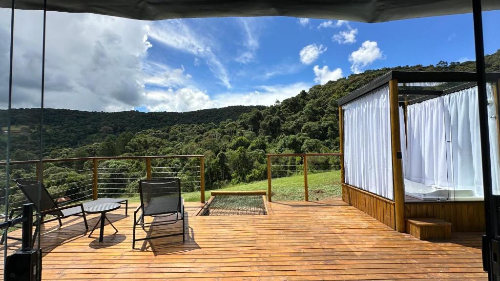 una terraza de madera con mesa y sillas. en Domo da Montanha, en Monte Verde