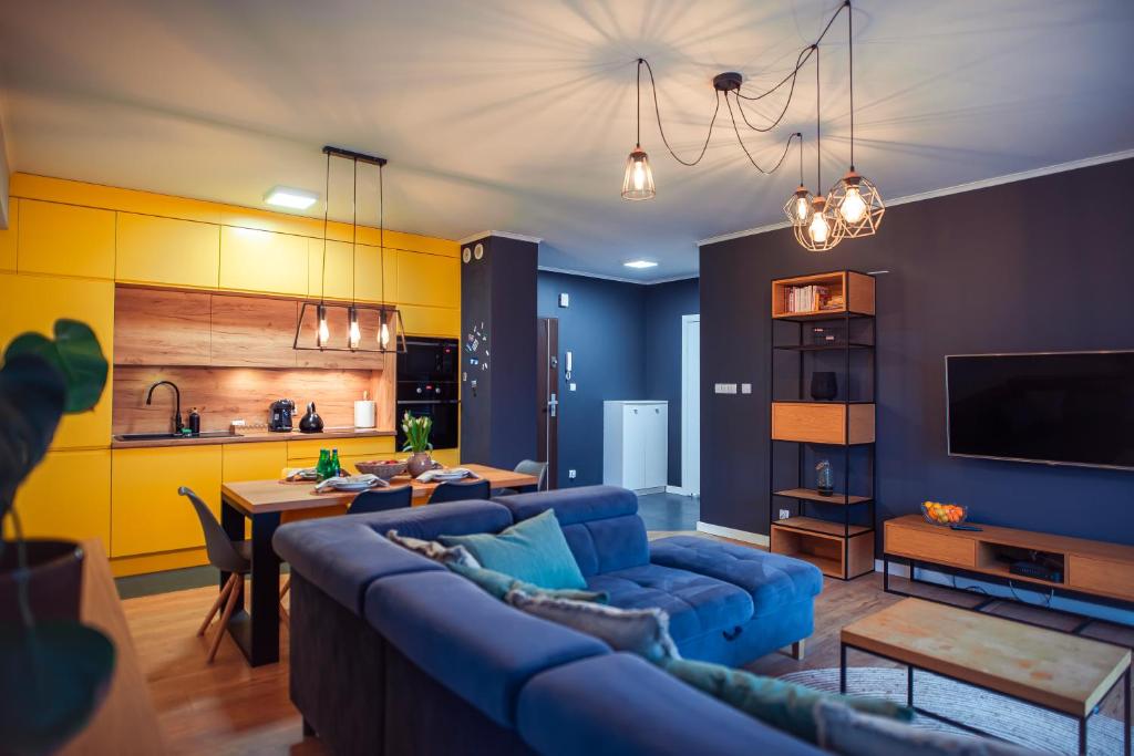 a living room with a blue couch and a kitchen at Apartament Słoneczny in Kwidzyn