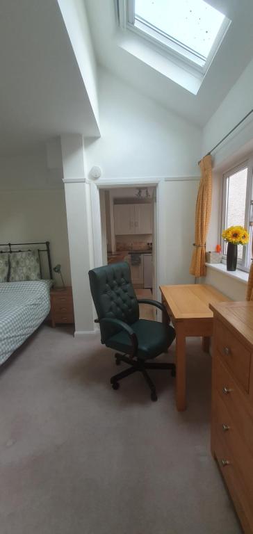 um quarto com uma cadeira verde e uma secretária em Merton House, fully serviced studio apartment em West Molesey
