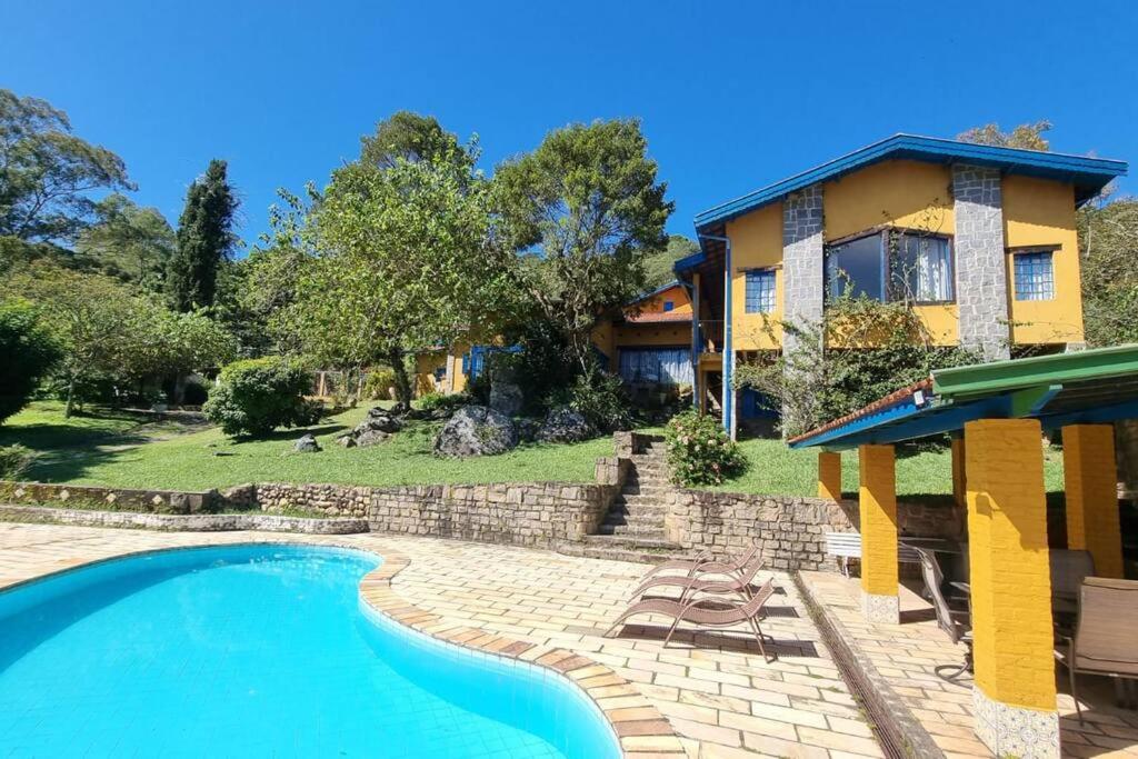 une maison avec une piscine en face d'une maison dans l'établissement Sitio Ramalhete - Sua escapada perfeita na Serra da Mantiqueira, à São Bento do Sapucaí