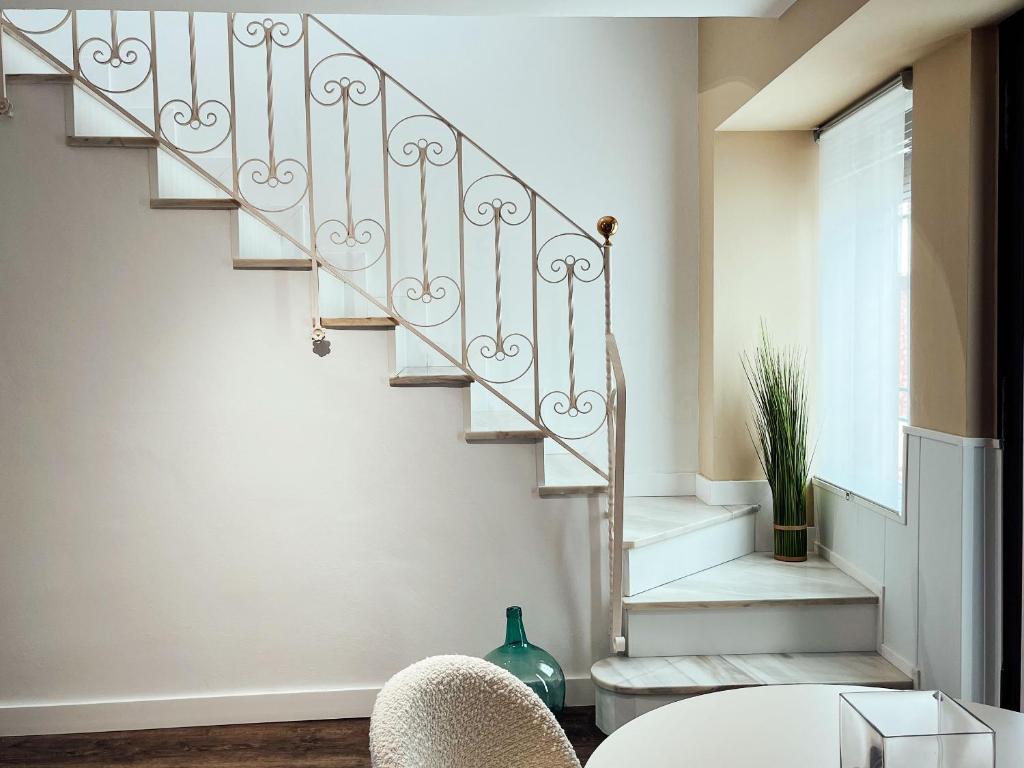 uma escada numa sala de estar com uma mesa e cadeiras em María Luisa Home em Priego de Córdoba