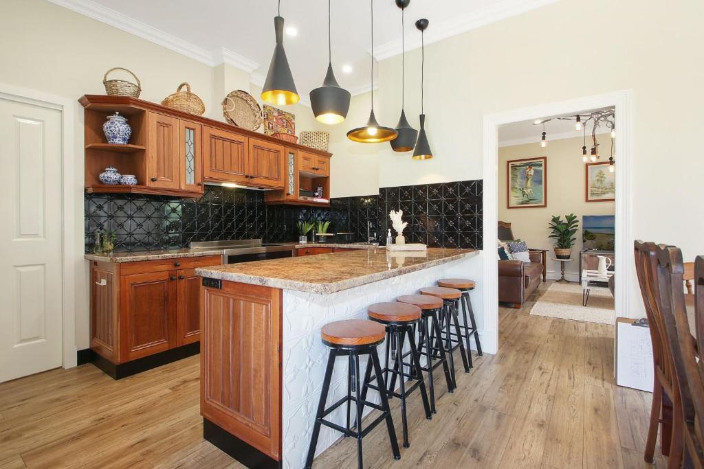una cucina con mobili in legno e sgabelli da bar di Orchard House a Beechworth