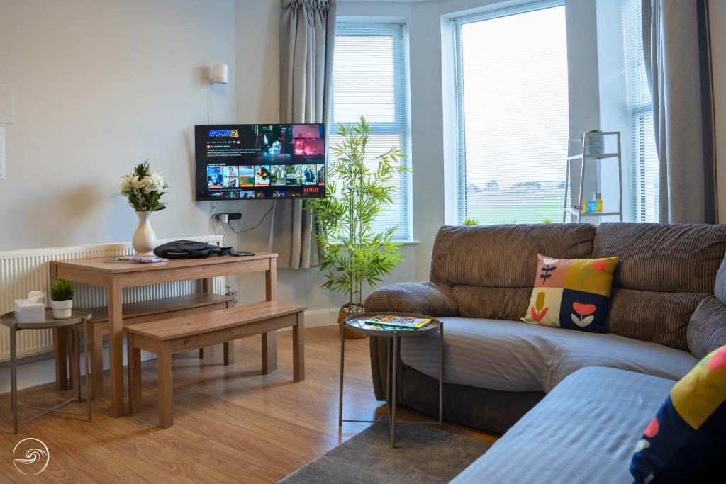 a living room with a couch and a tv at Portrush by the Sea - 2 Dunluce Green in Portrush