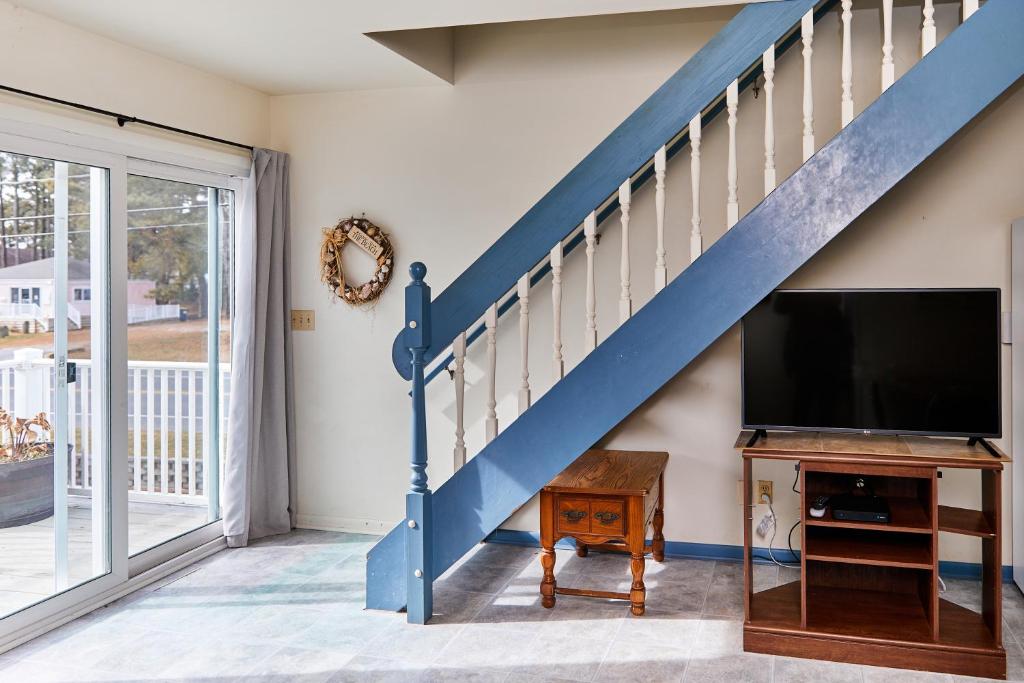 escalera azul y sala de estar con TV de pantalla plana. en Crush Villa, en Chincoteague