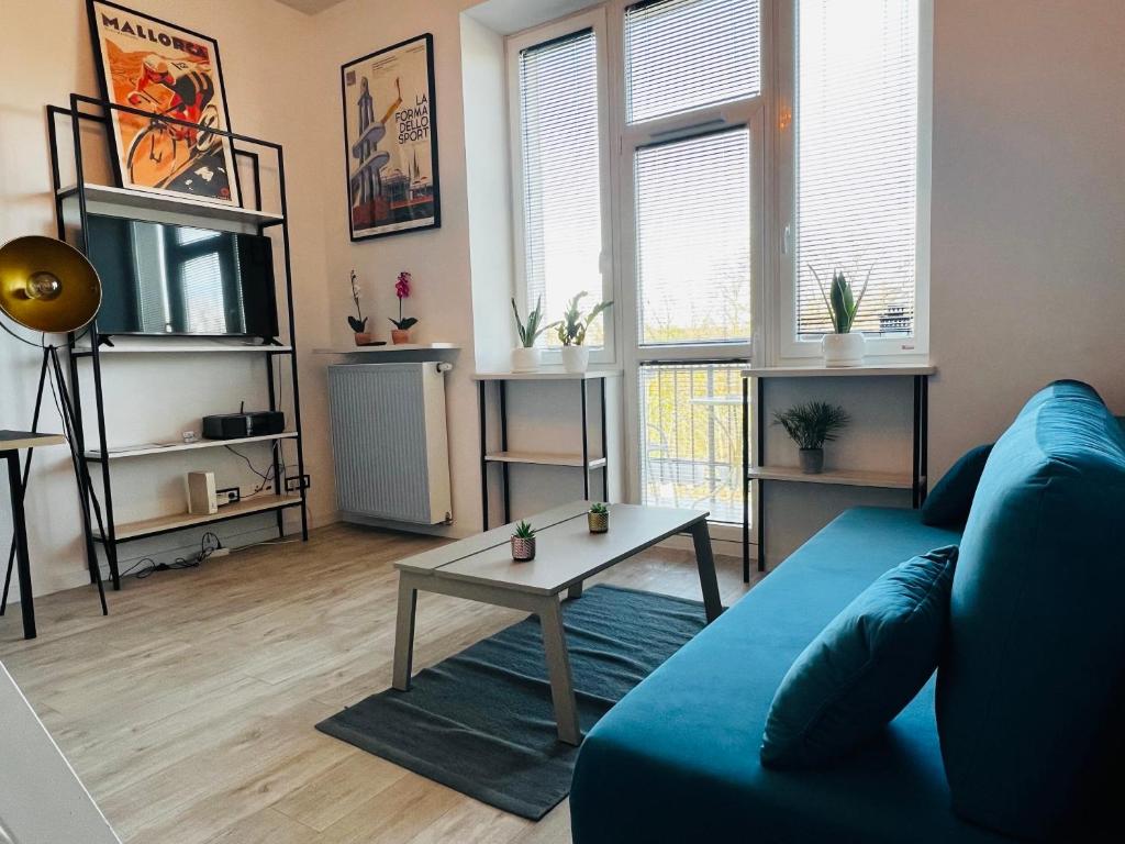 a living room with a blue couch and a table at Łazienki Krolewskie Studio z Antresolą i widokiem in Warsaw