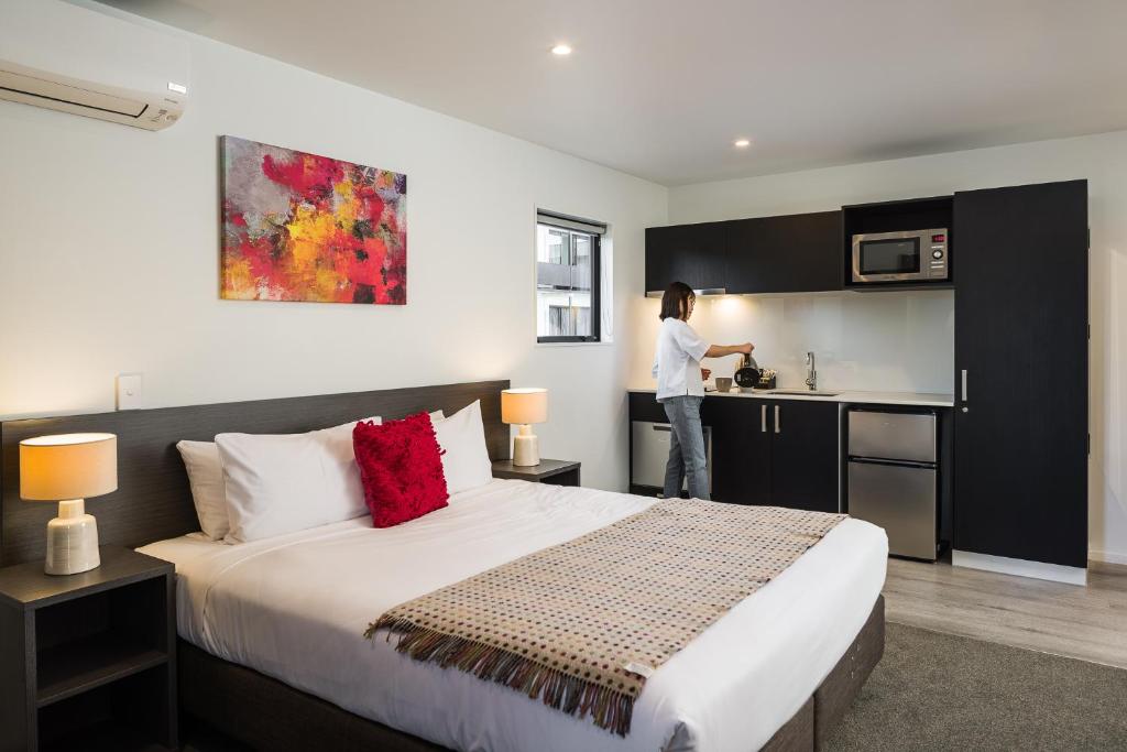 a woman standing in the kitchen of a hotel room at Carnmore Hagley Park in Christchurch