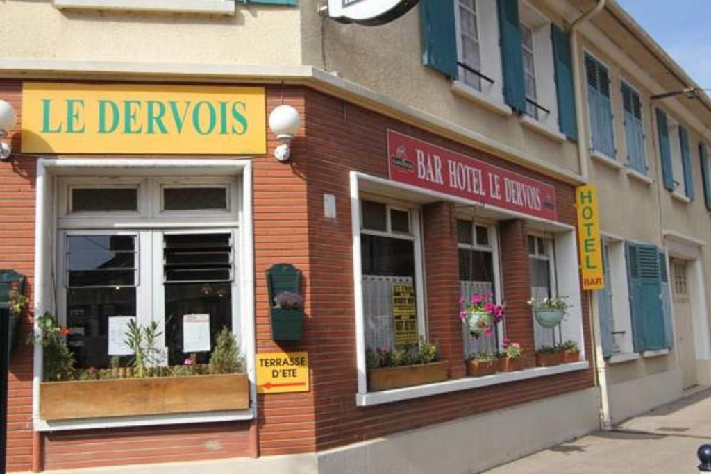 una tienda con flores en las ventanas de un edificio en Hôtel le Dervois, en Montier-en-Der