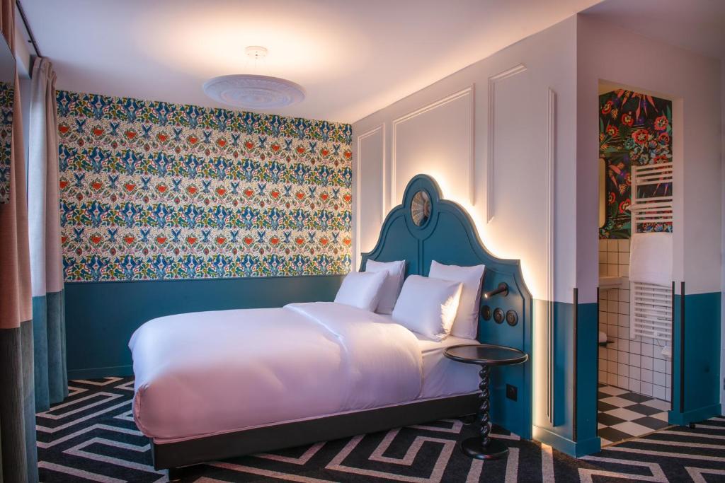 a bedroom with a white bed and a colorful wall at LABE Hôtel Tours Centre Gare in Tours