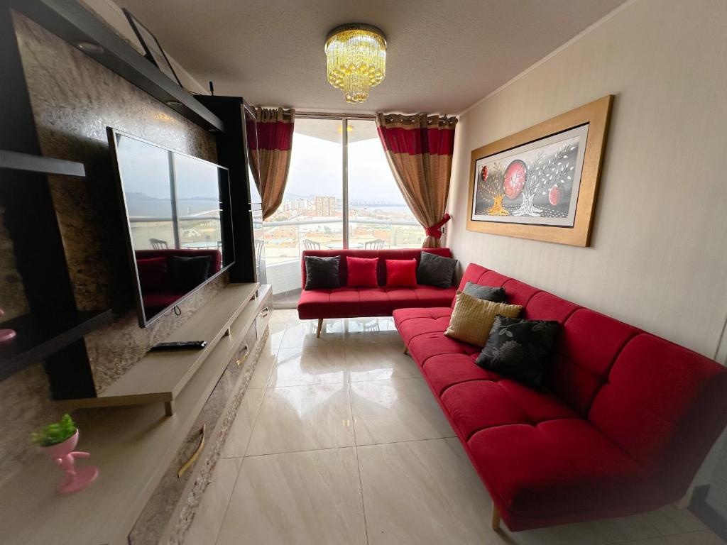 sala de estar con sofá rojo y TV en Con vista al mar en San Miguel, en Lima