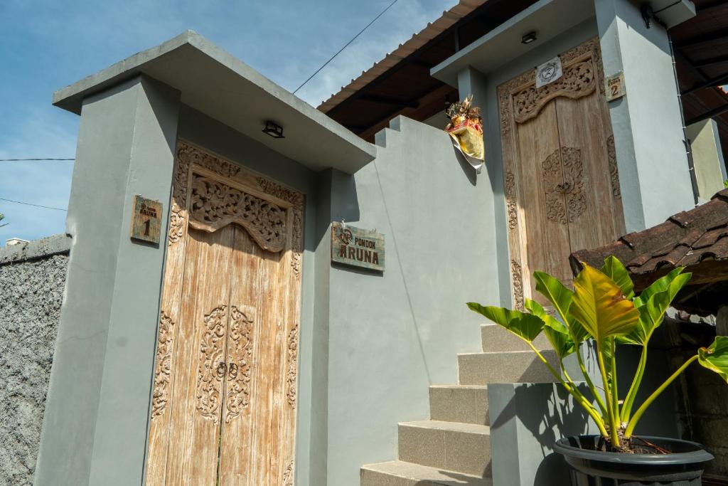 a house with wooden doors and a potted plant at Pondok Aruna in Ubud