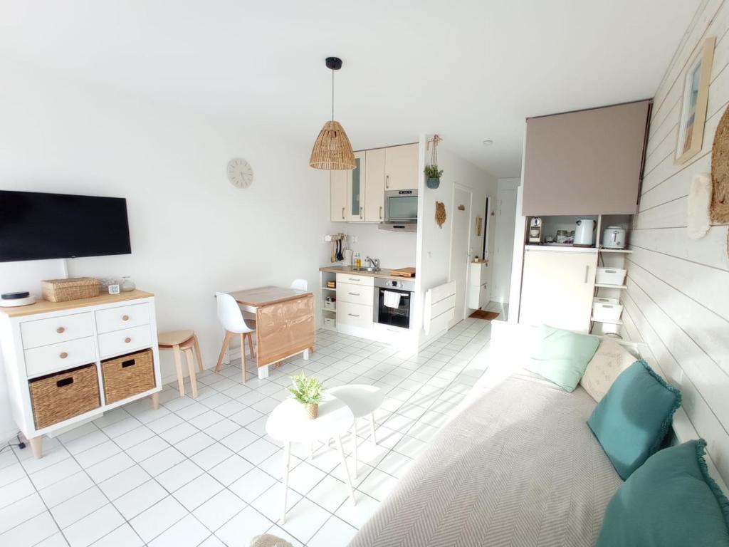 sala de estar con sofá y cocina en Cocon Moderne, Piscine, Parking, Proche Plage, en Guérande