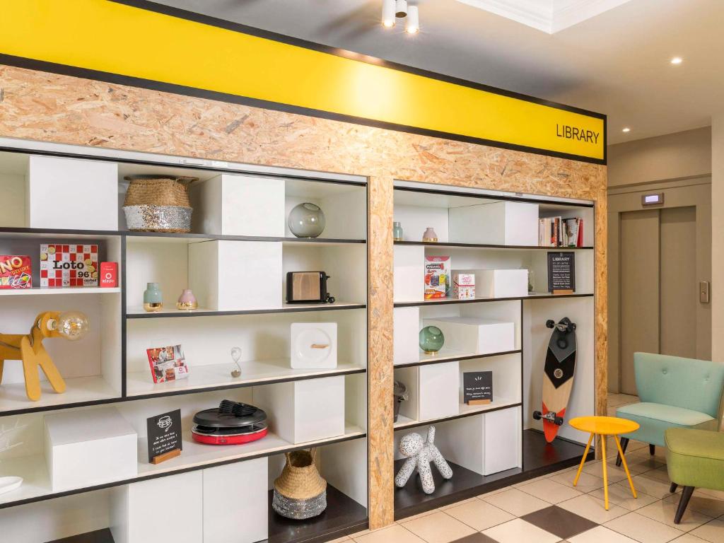 a room with white shelves and a yellow wall at Aparthotel Adagio Access Paris Vanves - Porte de Versailles in Vanves