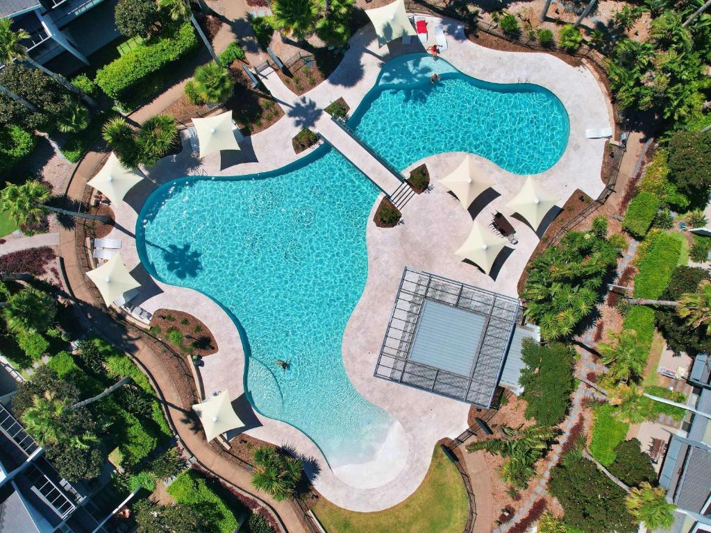 an overhead view of a swimming pool with a tennis court at Pullman Magenta Shores Resort in The Entrance