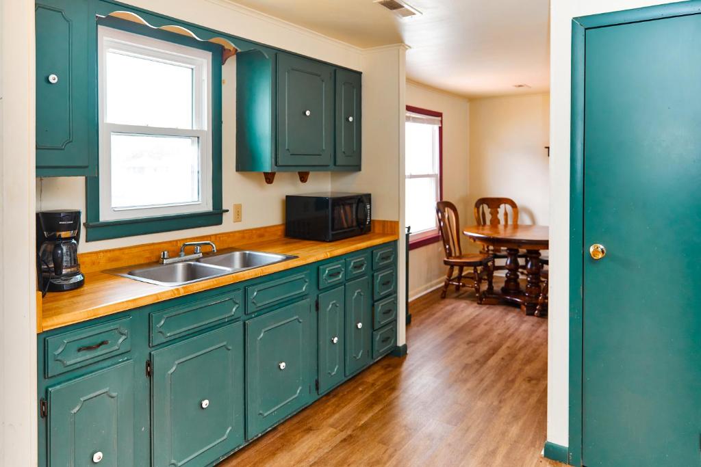 a kitchen with green cabinets and a sink and a table at Beach House @ The Reef in Chincoteague