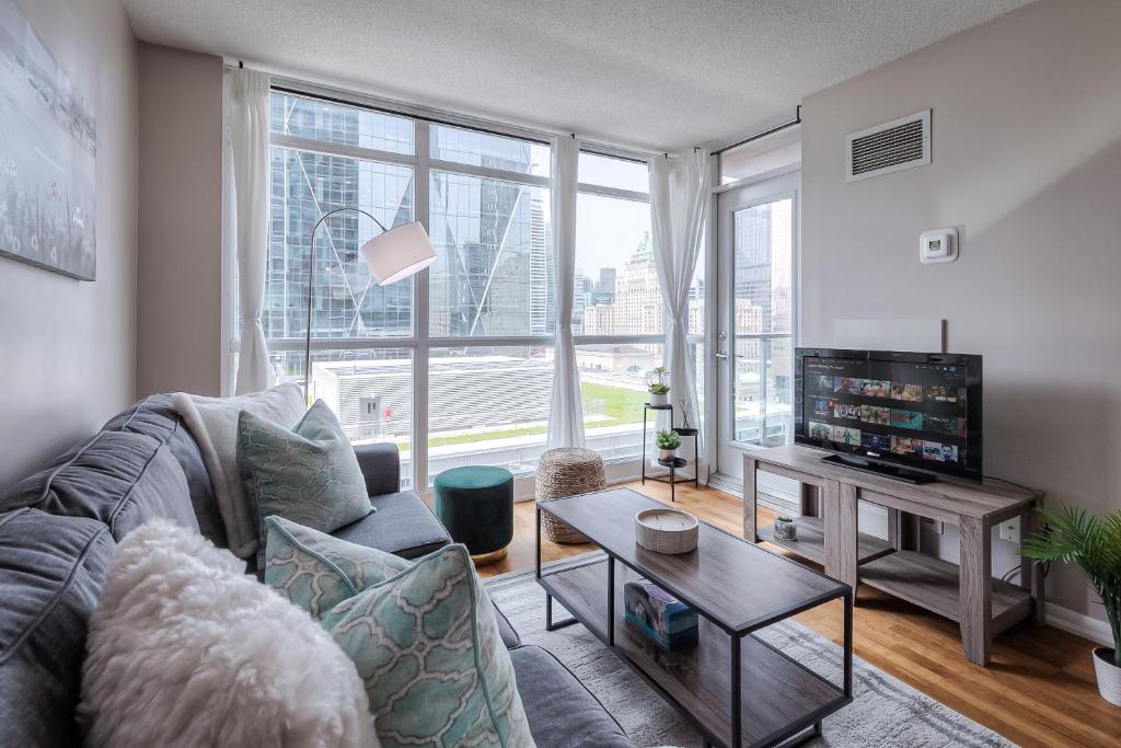 a living room with a couch and a tv at RivetStays - The Yonge in Toronto