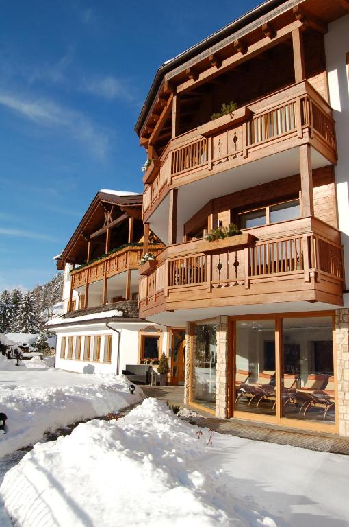 duży drewniany budynek z śniegiem przed nim w obiekcie Residence Sovara w mieście Santa Cristina Valgardena
