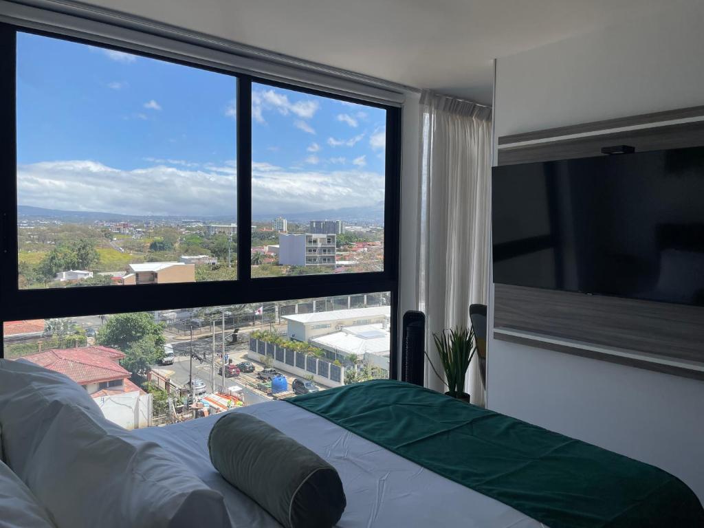 a bedroom with a view of a city from a window at SkyGarden Nunciatura Luxury Apartment in San José