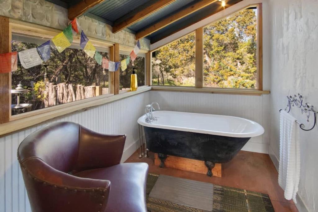 an old tub in a bathroom with a chair and a window at A Special Retreat on a Mini-Farm -- in SMTX in San Marcos