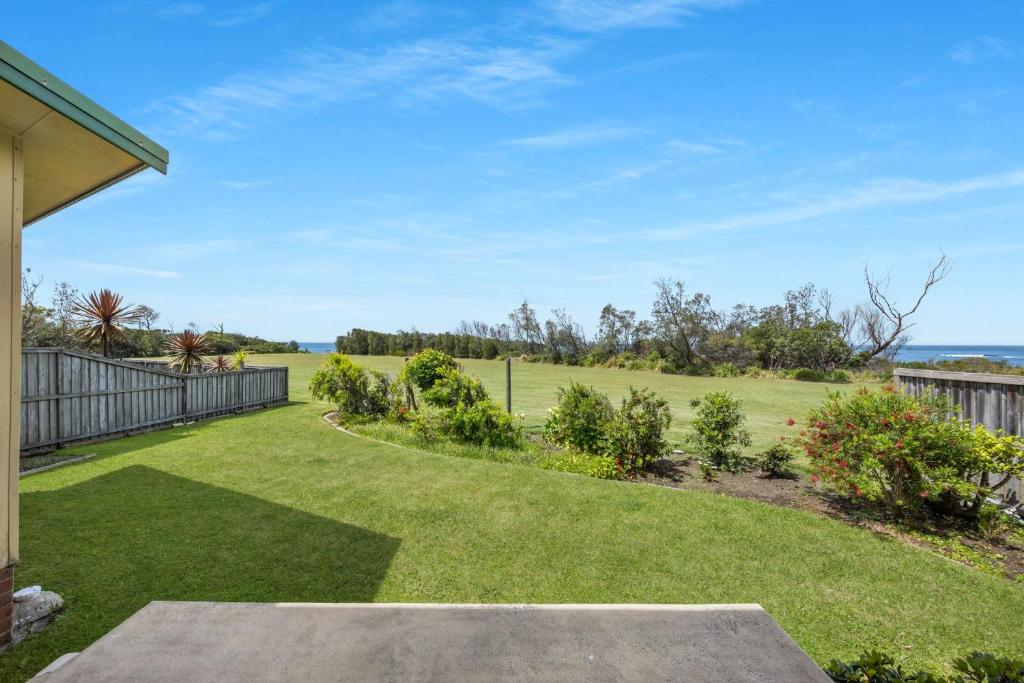 an open yard with a fence and a lawn at Beachside Cottage in Berrara
