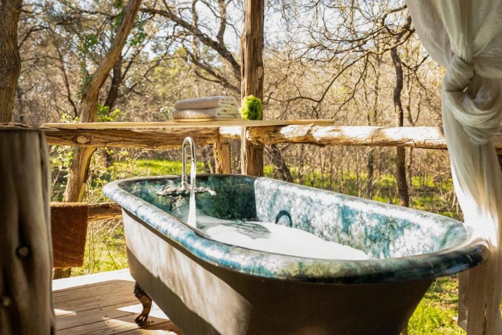 a bath tub sitting on a deck in a yard at A Rustic Romantic Getaway in Texas Hill Country in San Marcos
