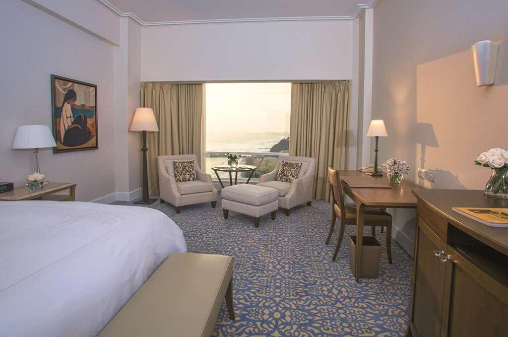 una camera d'albergo con letto, scrivania e sedie di Habitación queen para 2 a Lima