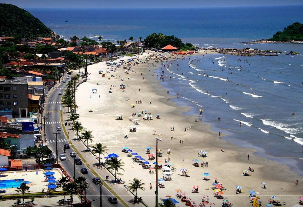 a beach with people and umbrellas and the ocean at Apartamento na Praia dos Sonhos Perto do Mar em Itanhaém in Itanhaém