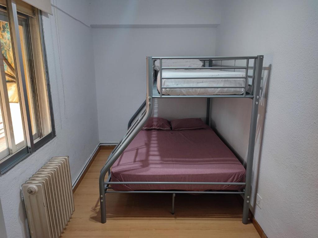 ein Metalletagenbett in einem Zimmer mit Fenster in der Unterkunft Sencillo Alcala in Alcalá de Henares