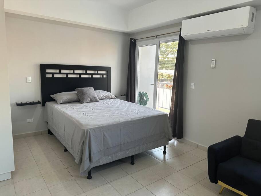 ein Schlafzimmer mit einem Bett, einem Stuhl und einem Fenster in der Unterkunft Apartamento en Villa Firenze in Tegucigalpa