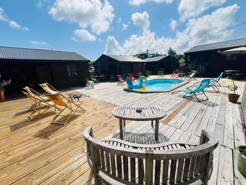 a deck with a pool and chairs and a table at les gites du cocon in Cadet