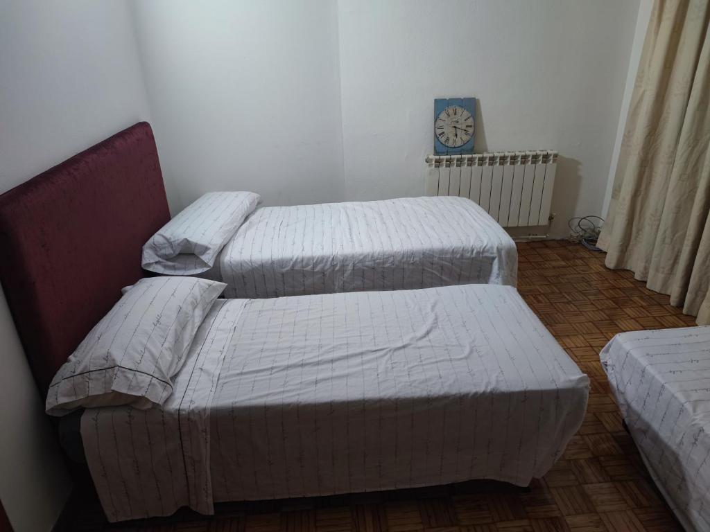 twee bedden in een kamer met een klok aan de muur bij Coslada parque blanco in Coslada