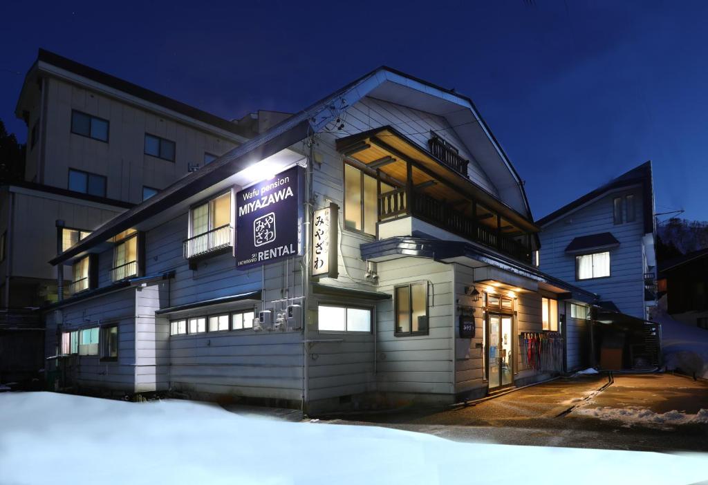 a building with a sign on the side of it at Nozawaonsen Guest House Miyazawa in Nozawa Onsen