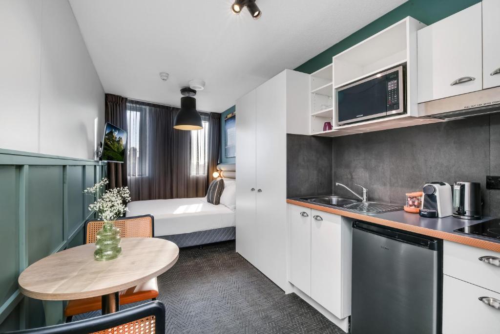 a kitchen with a small table and a room with a bed at The Urban Newtown in Sydney