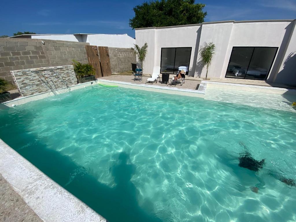 a swimming pool with blue water in front of a house at CABAÑA PARA VACACIONAR EN SABANAGRANDE in Sabanagrande