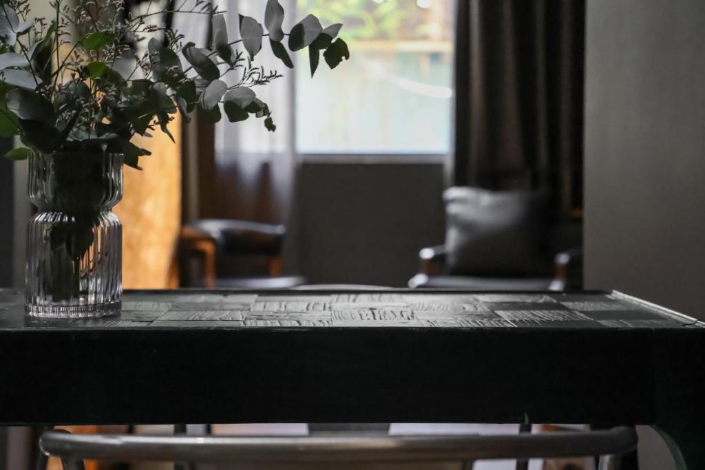 a black table with a vase of flowers on it at The Urban Newtown in Sydney