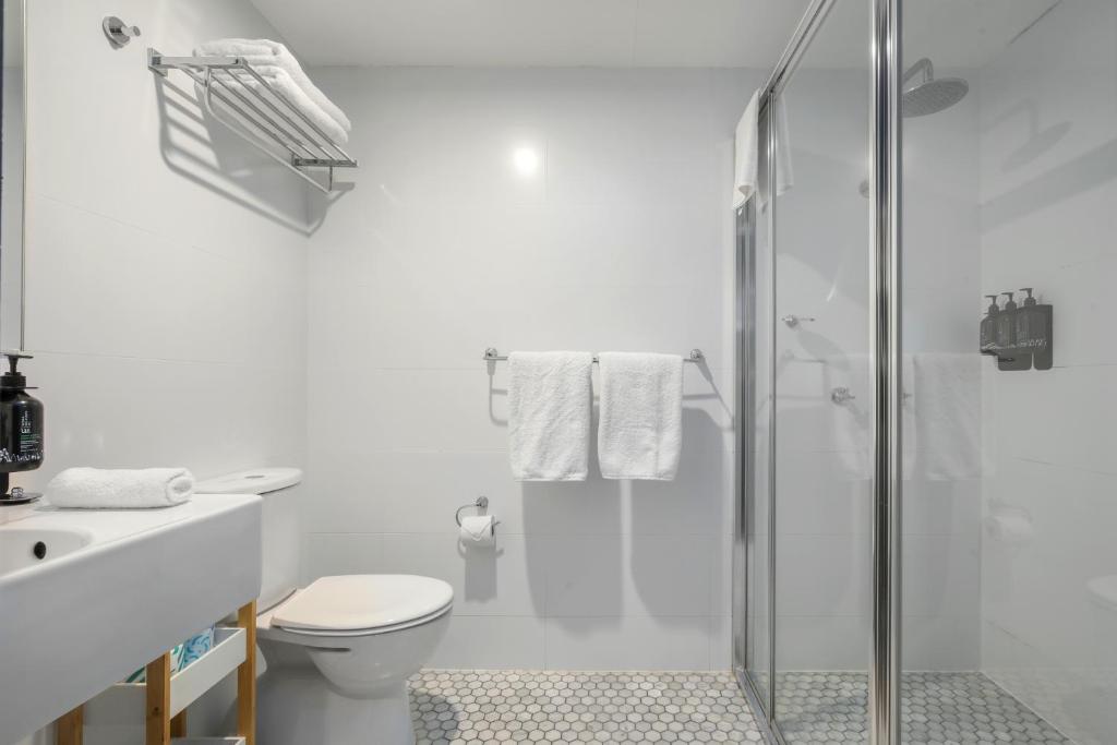 a white bathroom with a toilet and a shower at The Urban Newtown in Sydney