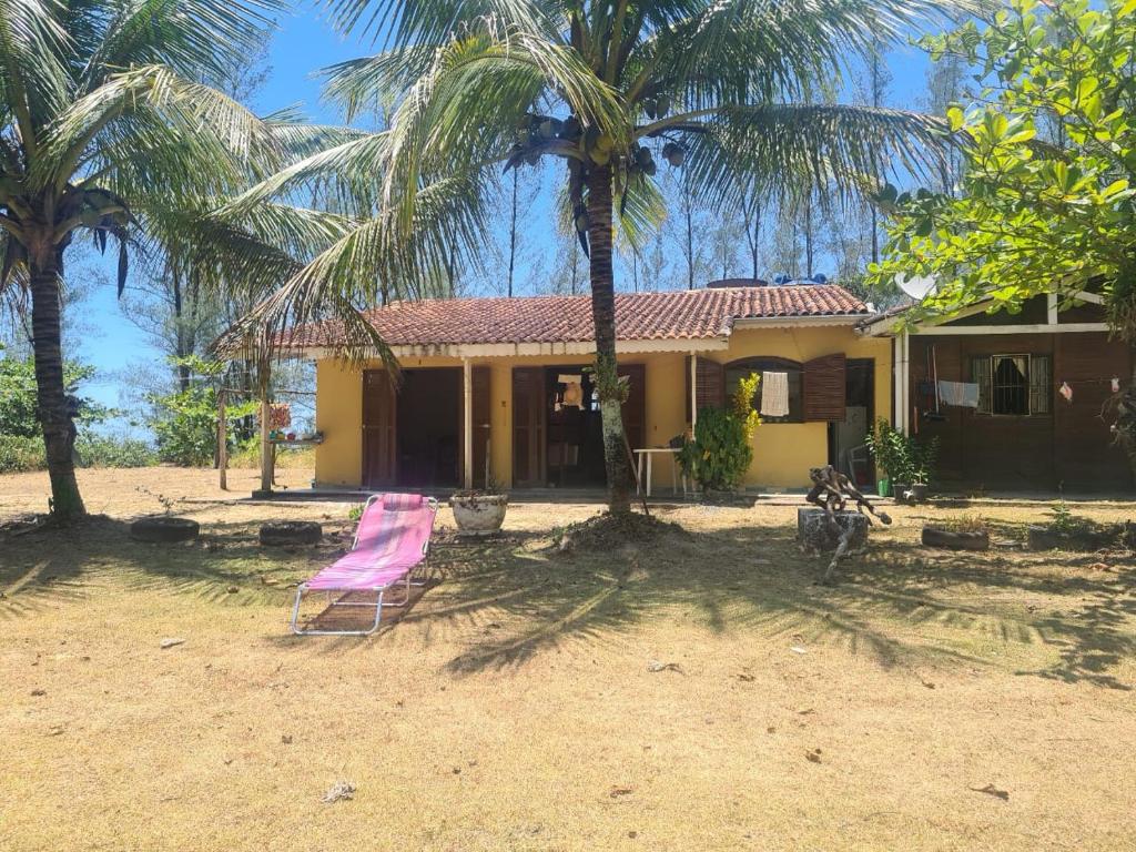 una casa con una silla rosa delante en Casa de veraneio, en Ilha Comprida