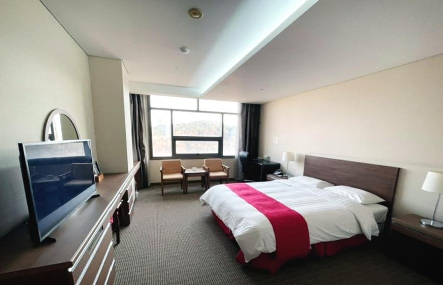 um quarto de hotel com uma cama e uma televisão em Ramada by Wyndham Dongtan em Hwaseong