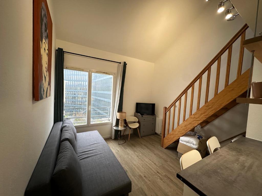 Hotel 2 pièces duplex Issy Les Moulineaux Ascenseur internet, a living room with a couch and a staircase at 2 pièces duplex Issy Les Moulineaux Ascenseur internet in Issy-les-Moulineaux