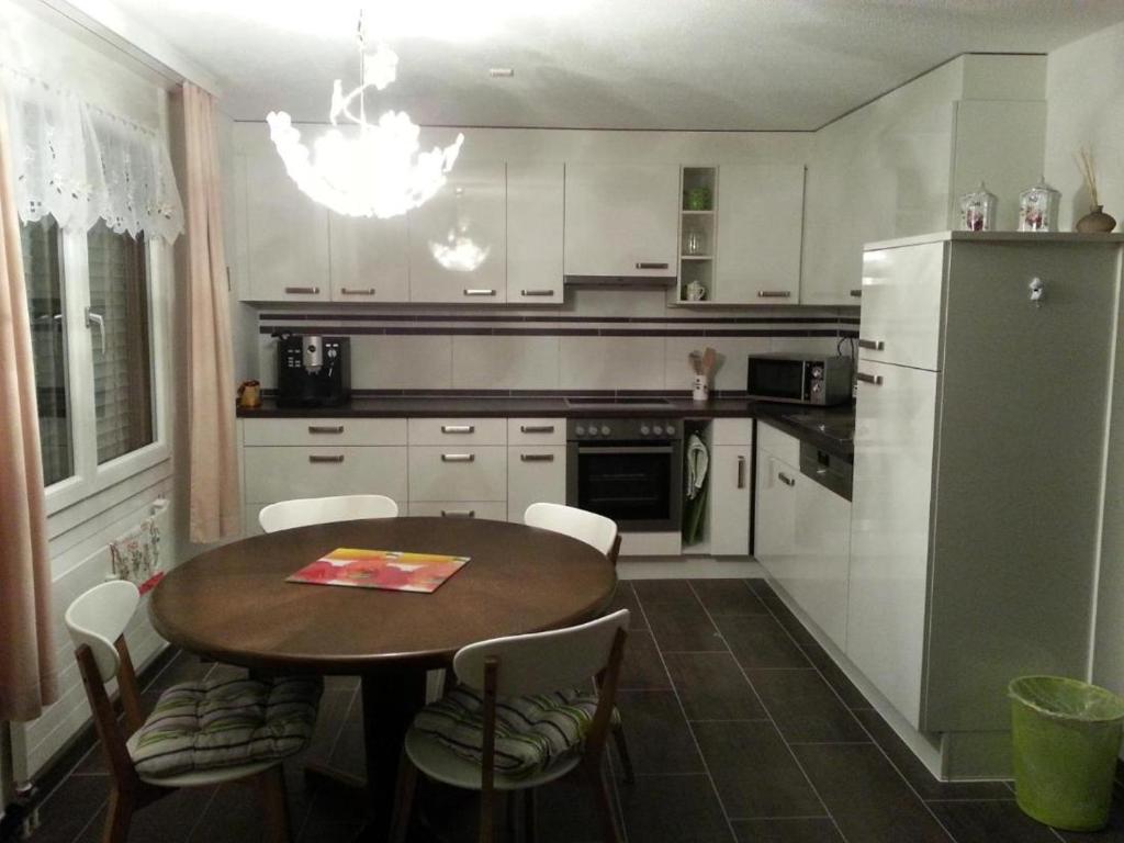 a kitchen with a table and chairs and a refrigerator at Elfe-Apartments Two-room Apartment with Garden, 2-4 guests in Emmetten