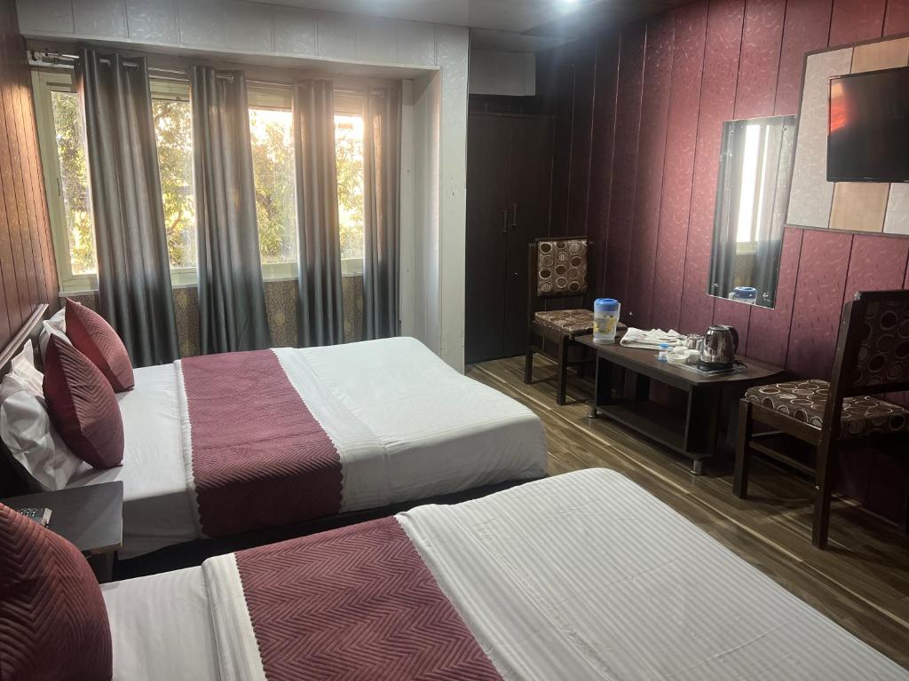 a hotel room with two beds and a desk and a mirror at Hotel The Amar Grand in Mussoorie