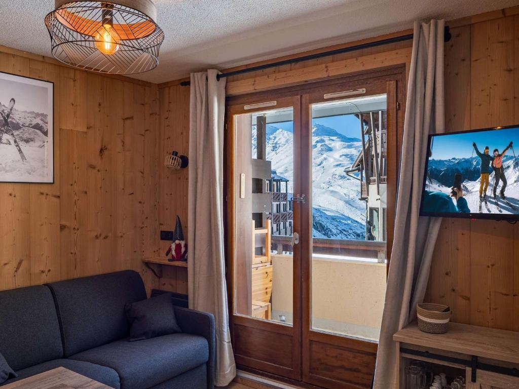 un salon avec un canapé, une télévision et une fenêtre dans l'établissement Appartement Moderne à Val Thorens - 4 pers, 1 Chambre + Cabine, Balcon Sud, Ski aux Pieds - FR-1-637-74, à Val Thorens
