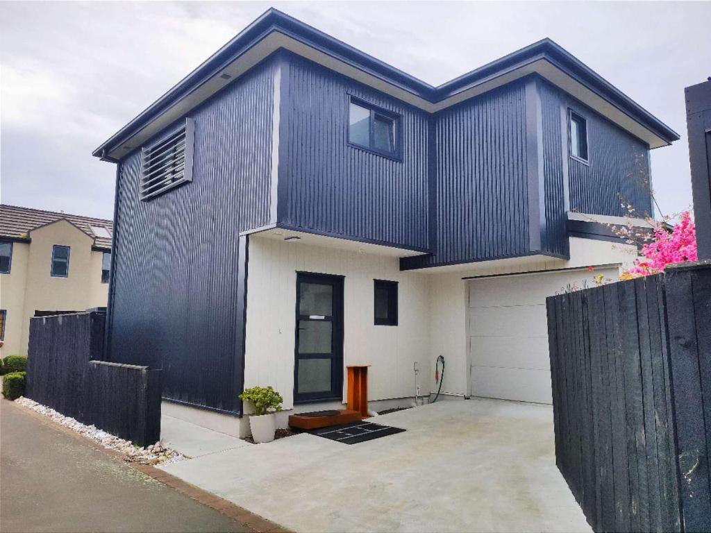 una casa en blanco y negro con garaje en LilyのHome Elegant Retreat near Riccarton Mall, en Christchurch