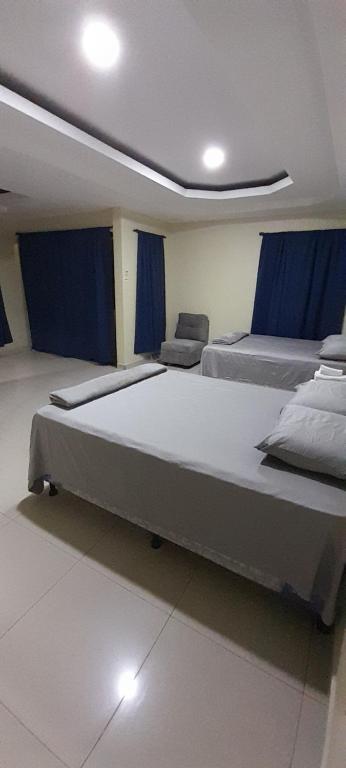2 ampi letti in una camera con tende blu di Espacioso en zona exclusiva a Santa Rosa de Copán