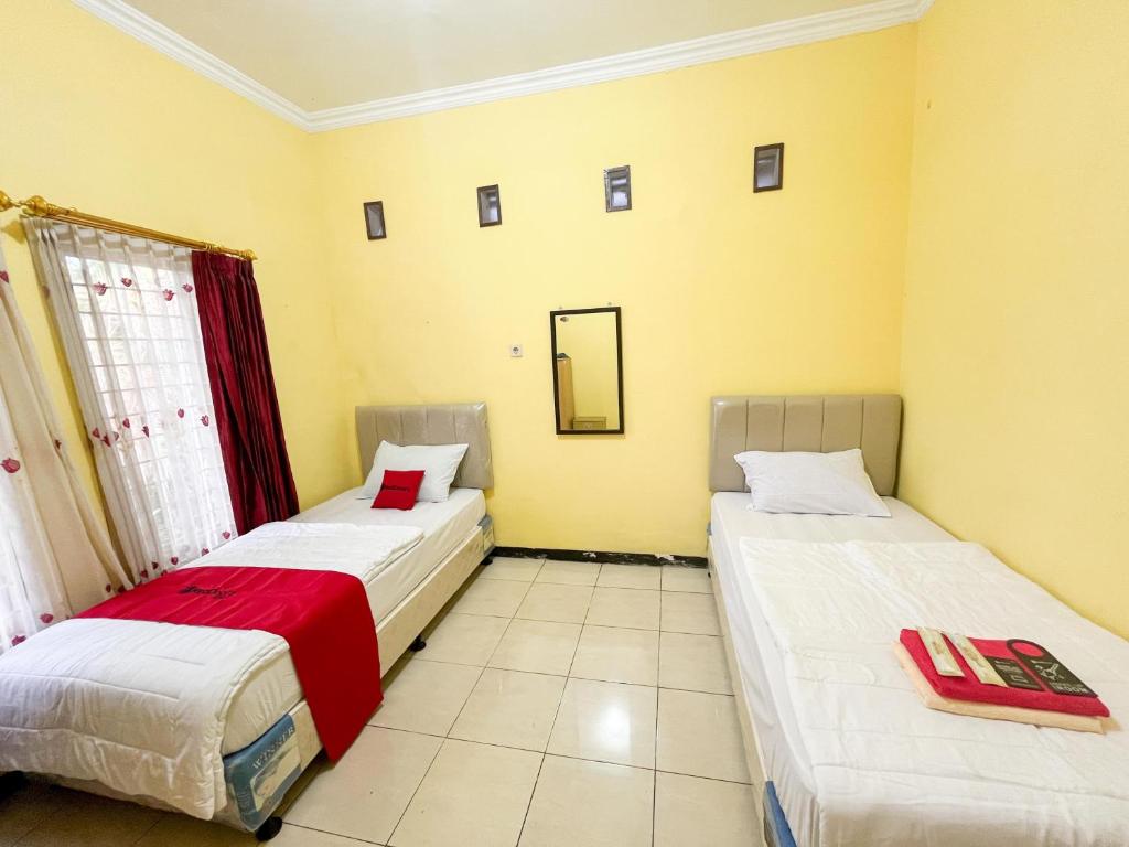 two beds in a room with yellow walls at Reddoorz Near BNS 2 in Tlekung