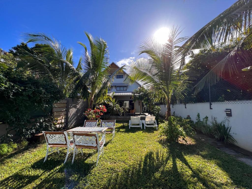 un patio trasero con mesa, sillas y palmeras en Tropical 3-bedrooms Coastal Residence Creolia en Grand Baie