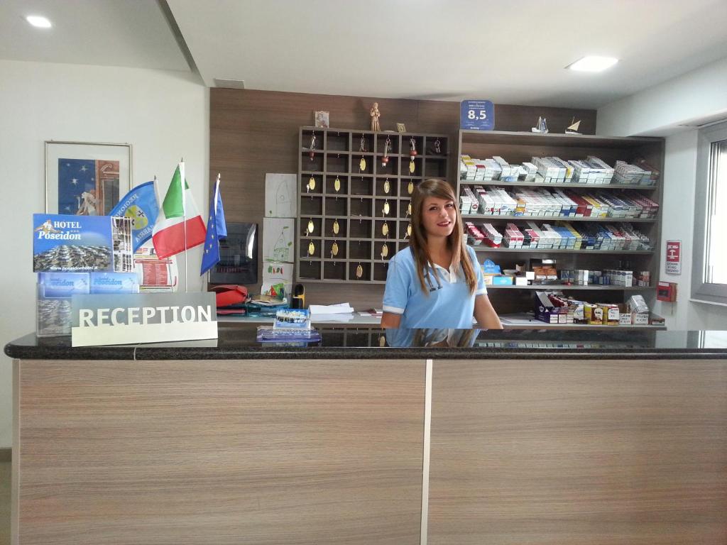 コリリアーノ・カーラブロにあるHotel Poseidonの薬局の窓口に立つ女