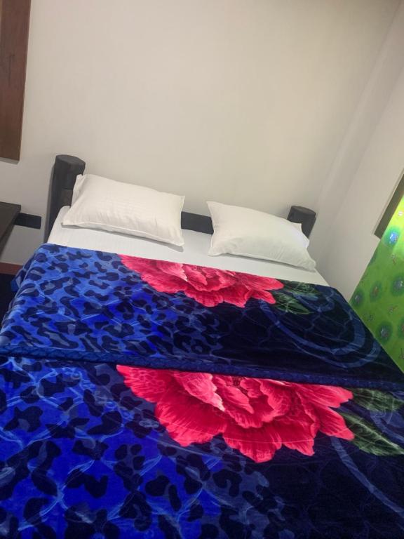 a bed with a blue and red flower quilt on it at Micro wood cabana in Nuwara Eliya