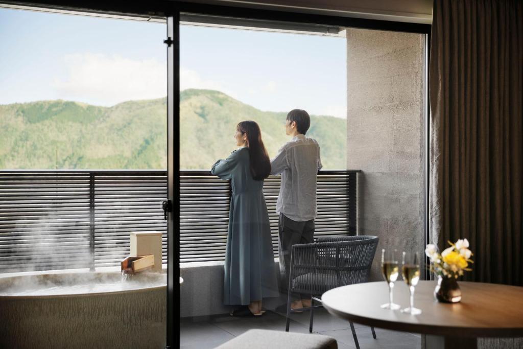 Ein Mann und eine Frau, die aus dem Fenster schauen in der Unterkunft Laforet Hakone Gora Yunosumika in Hakone