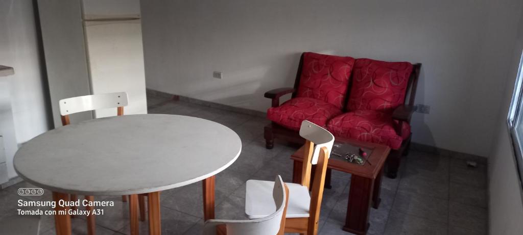 uma sala de estar com uma mesa e um sofá vermelho em La posada del viento em Villa El Rincón